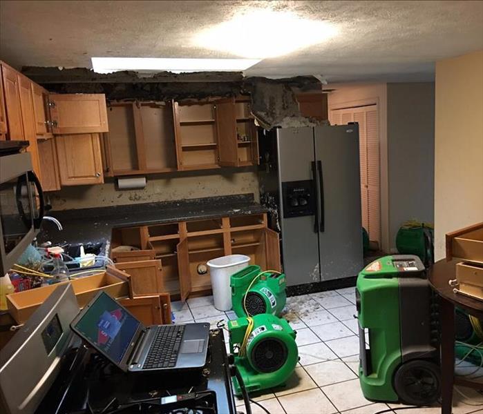 kitchen in disarray with servpro equipment helping to dry from a burst pipe 