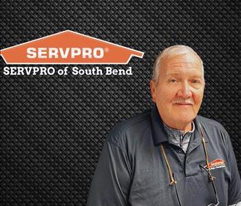 Man looking at the screen on a black background with a servpro logo on the wall