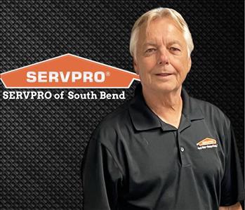 man smiling at the camera with a black background and a SERVPRO logo