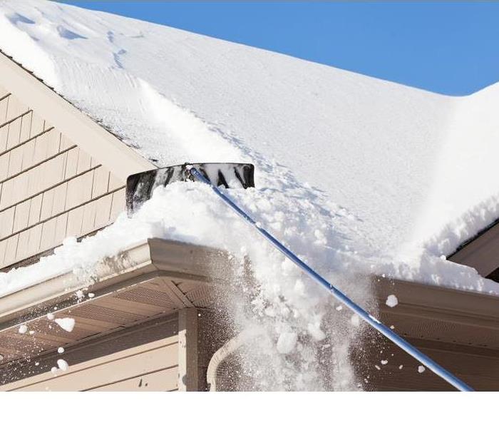 snow rake being used on a roof to help eliminate ice dams from forming  