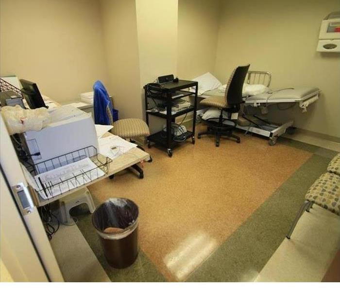 a healthcare room with gurney, printer and trashcan 